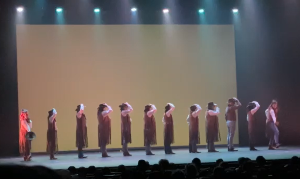 ESCENARIO DE TEATRO CON UN GRUPO DE BAILARINES DE FUNKY VESTIDOS DE COWBOYS CON SOMBRERO CHALLECO DE FLECOS Y VAQUEROS